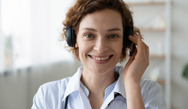 Smiling female doctor wearing headset looking at camera. Remote online medical chat consultation, telemedicine distance services, virtual physician conference call concept. Head shot close up portrait